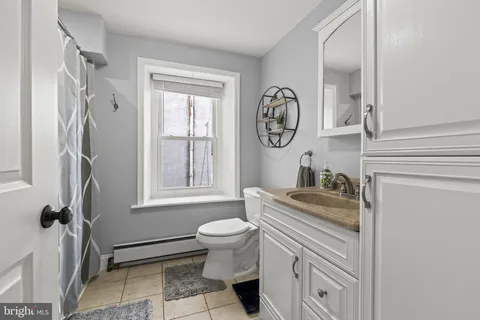 a bathroom with a granite countertop sink a toilet and a window