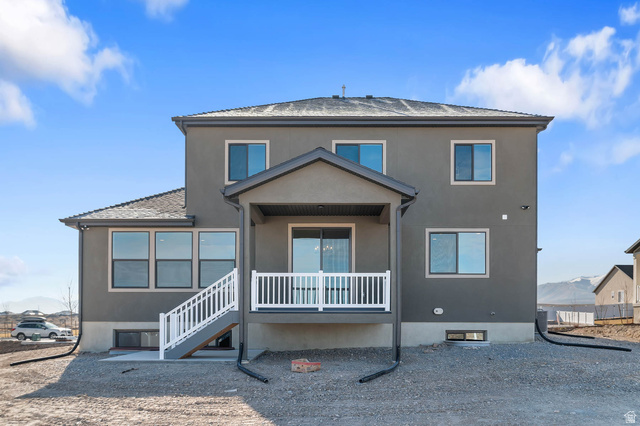 562 West Coyote Rdg Road Grantsville, UT 84029 - Photo 5 of 27 Exterior rear facade featuring a covered patio with white railings, a lower-level concrete pad, and multiple windows across two stories