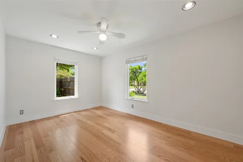 an empty room with windows and chandelier fan