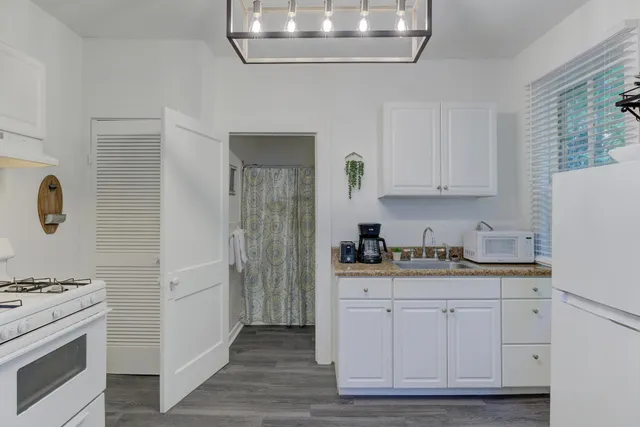 a kitchen with granite countertop white cabinets and white appliances