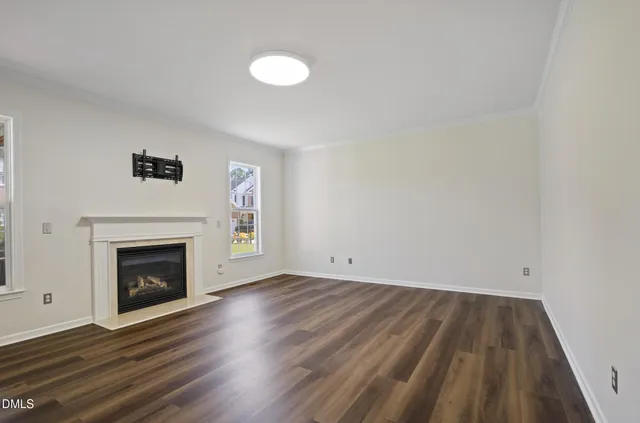 a view of empty room with wooden floor and fireplace