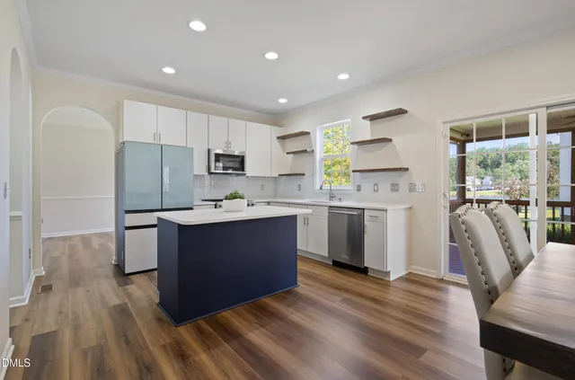 a kitchen with kitchen island wooden floors white appliances and cabinets