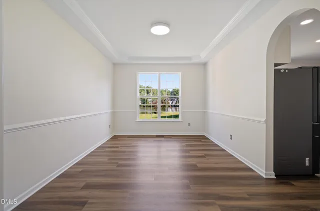an empty room with wooden floor cabinet and windows