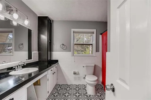 a bathroom with a granite countertop toilet sink and mirror