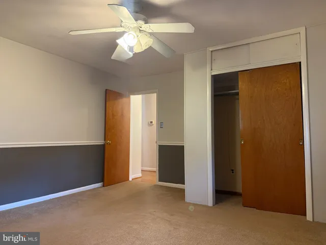 an empty room with closet and a ceiling fan