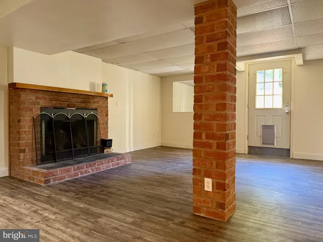 a view of a livingroom with wooden floor a fireplace and window