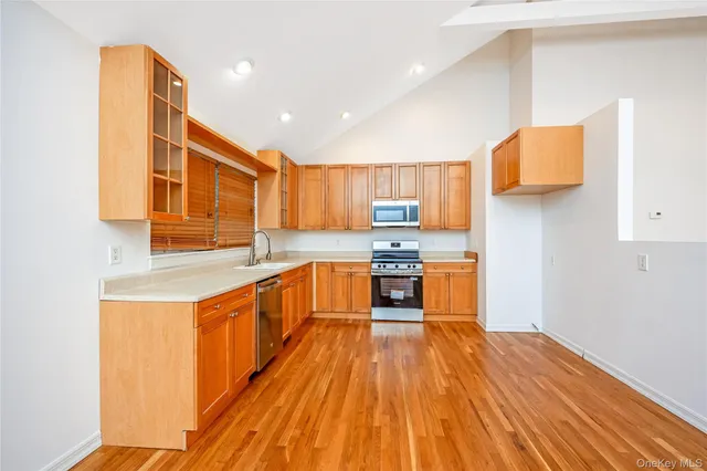 a kitchen with stainless steel appliances granite countertop wooden cabinets a sink and dishwasher a stove with wooden floor