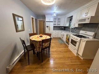 15 Paradiso Street, Unit 1 Norwalk, CT 06854 - Photo 4 of 16 a kitchen with stainless steel appliances granite countertop a stove a refrigerator a kitchen island a dining table and chairs with wooden floor