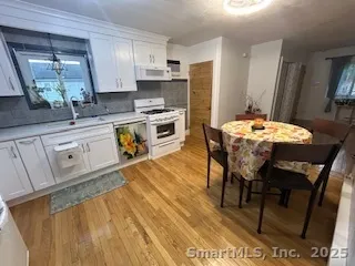 a kitchen with stainless steel appliances granite countertop a stove a sink dishwasher and a refrigerator with wooden floor