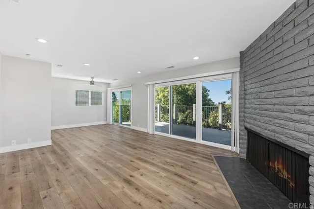 a view of an empty room with wooden floor and a fireplace