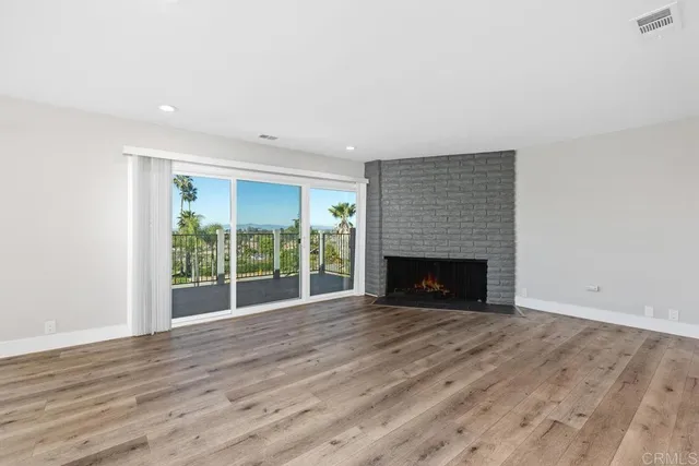 a view of empty room with wooden floor and fireplace