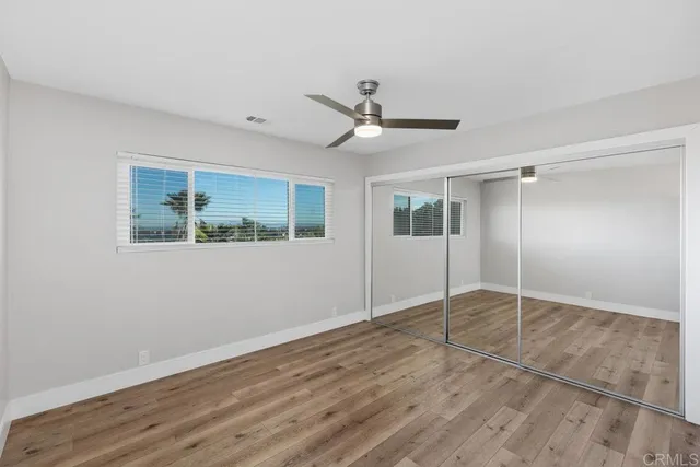 a view of empty room with wooden floor and ceiling fan