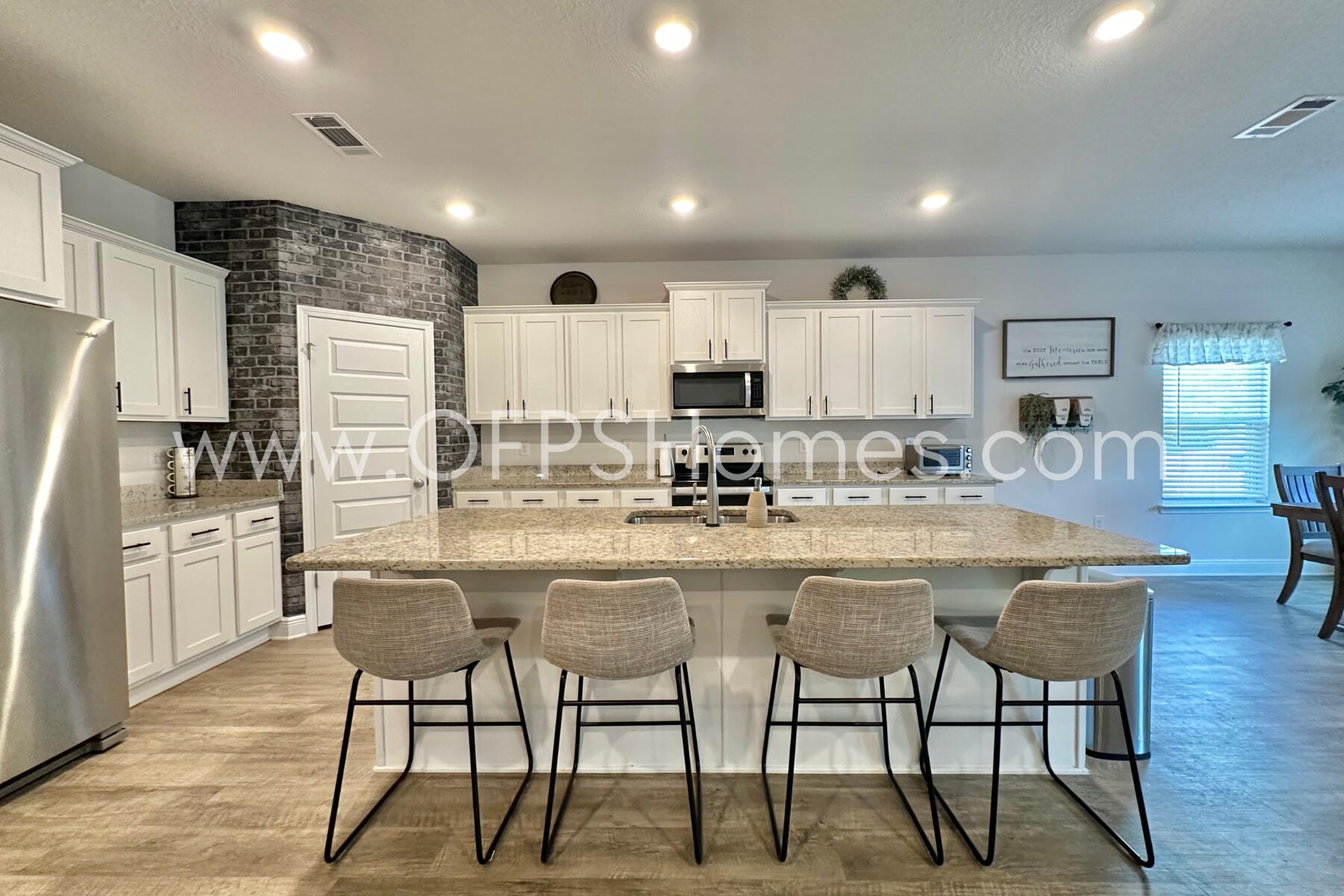 8090 Silver Maple Drive Milton, FL 32583 - Photo 15 of 42 a kitchen with stainless steel appliances a table chairs refrigerator and cabinets