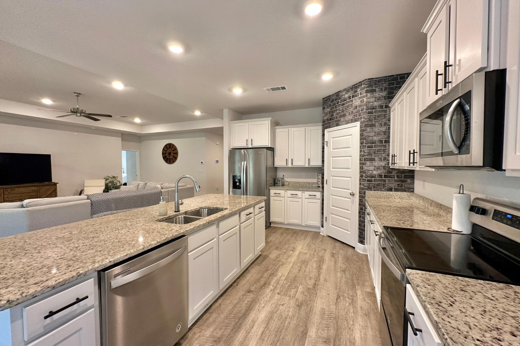 8090 Silver Maple Drive Milton, FL 32583 - Photo 16 of 42 a large kitchen with stainless steel appliances granite countertop a lot of counter space and wooden floor