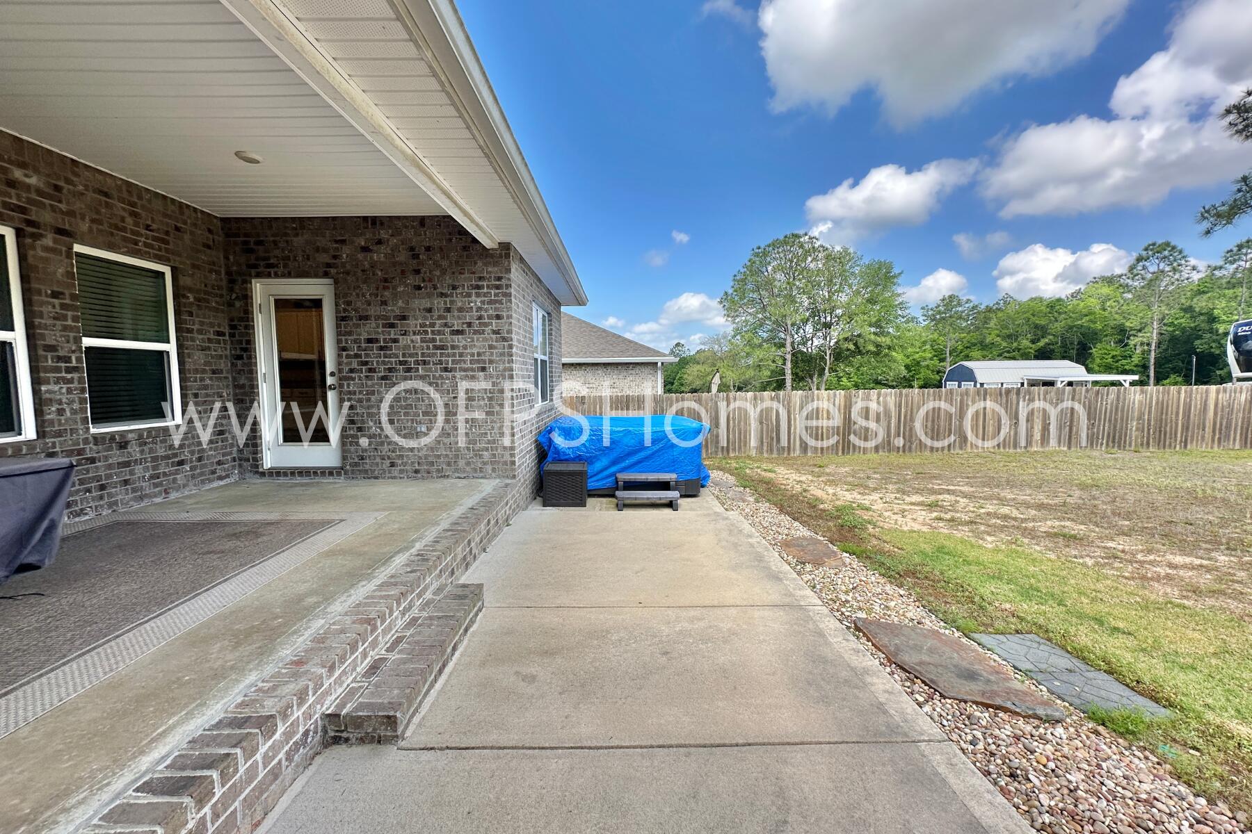 8090 Silver Maple Drive Milton, FL 32583 - Photo 40 of 42 a view of a patio with table and chairs with wooden floor and fence