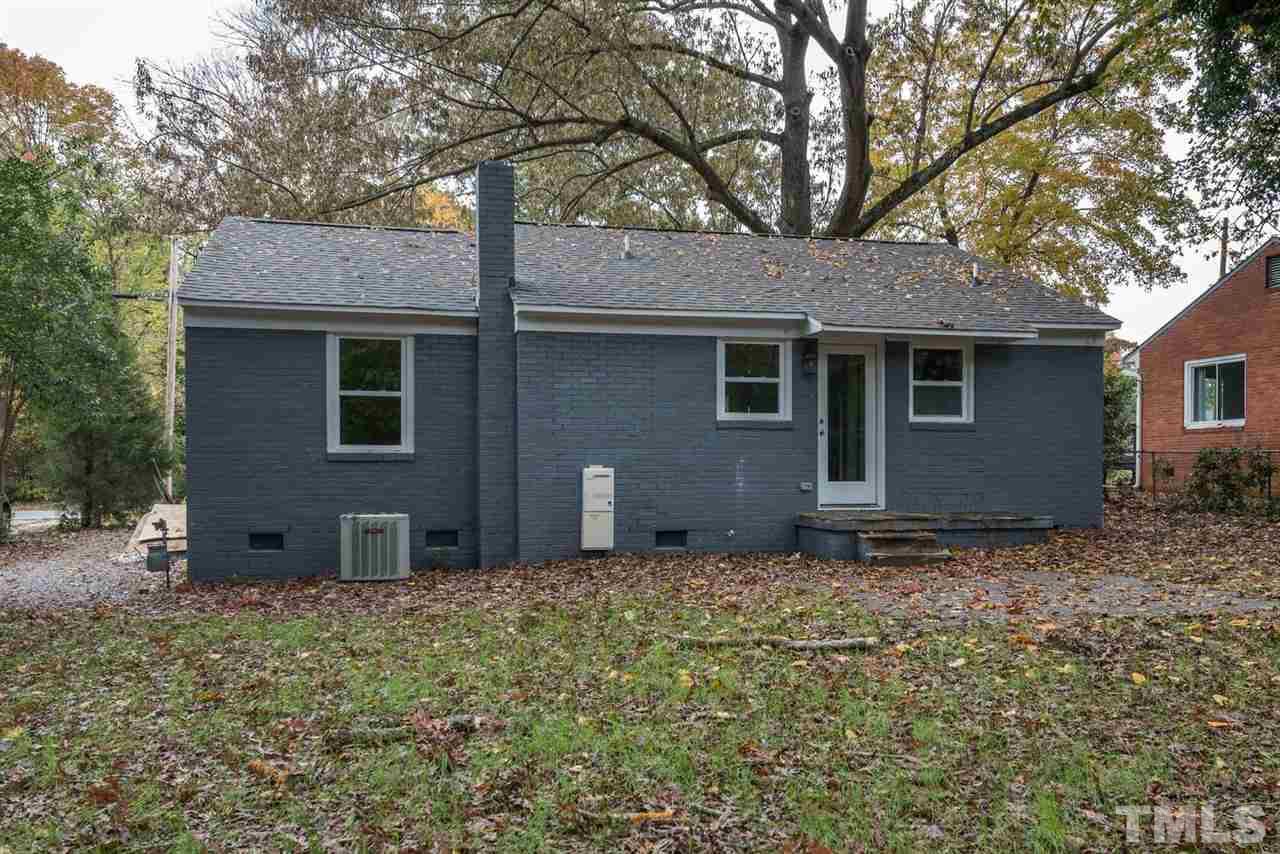 2408 Milburnie Road Raleigh, NC 27610 - Photo 25 of 25 a backyard of a house with large trees and brick walls