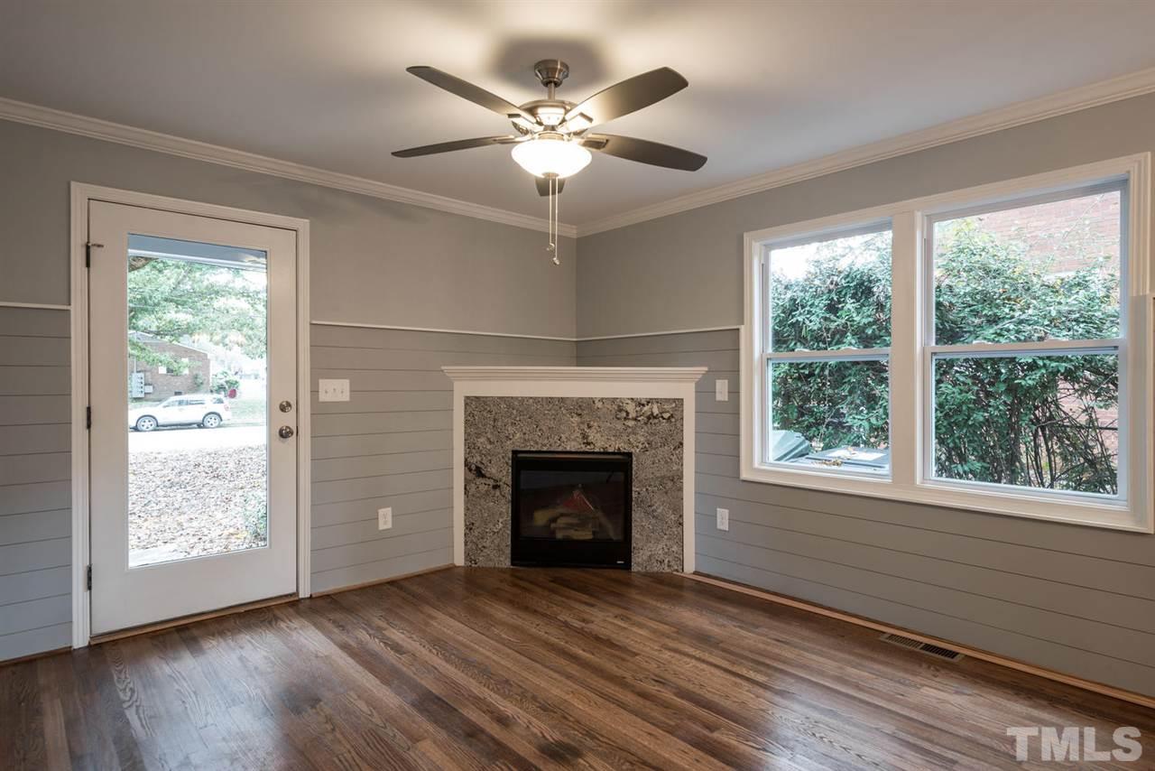 2408 Milburnie Road Raleigh, NC 27610 - Photo 6 of 25 a view of an empty room with wooden floor and a fireplace