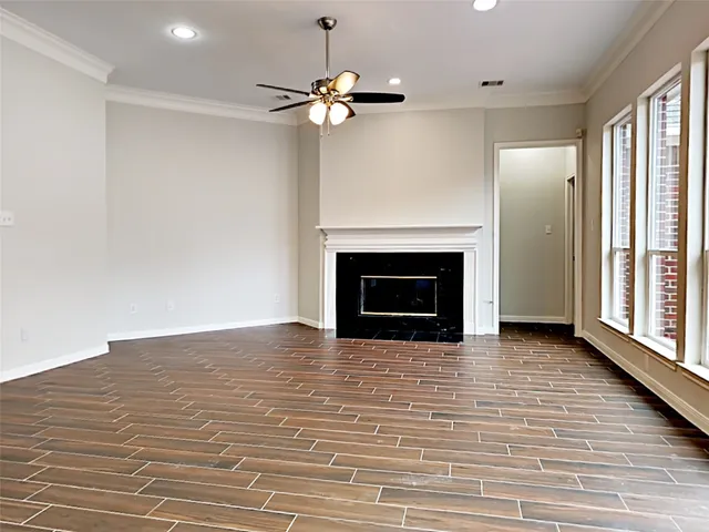 a view of an empty room with wooden floor fireplace and a window