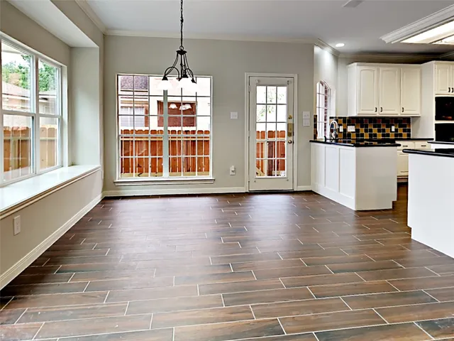 a view of an empty room with kitchen and window
