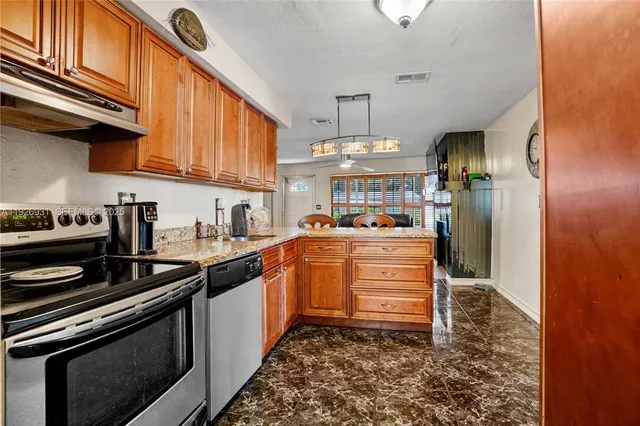 a kitchen with stainless steel appliances granite countertop a sink a stove and a refrigerator