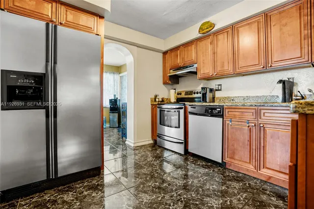 a kitchen with stainless steel appliances granite countertop a refrigerator a stove a sink and dishwasher
