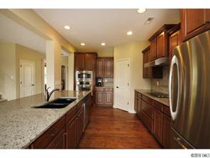 1305 Ridgehaven Road, Unit 165 Waxhaw, NC 28173 - Photo 5 of 16 a kitchen with granite countertop a sink refrigerator and cabinets