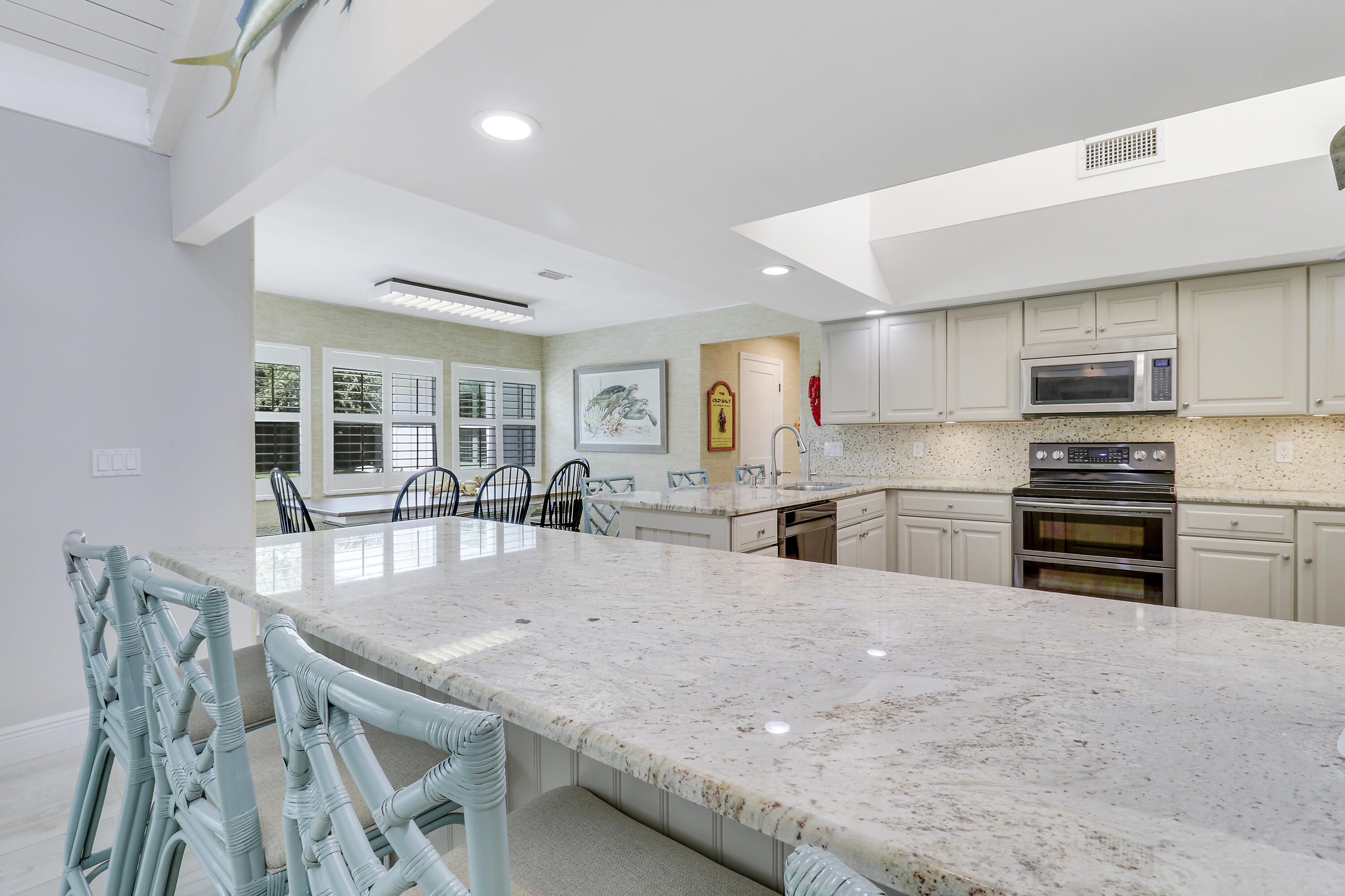 6372 North 197th Place Jupiter, FL 33458 - Photo 10 of 77 a kitchen with stainless steel appliances granite countertop a stove a refrigerator a sink a dining table and chairs