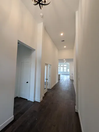 a view of a hallway with wooden floor and a bathroom
