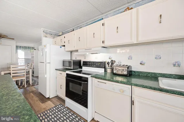 a kitchen with granite countertop a sink a stove and refrigerator