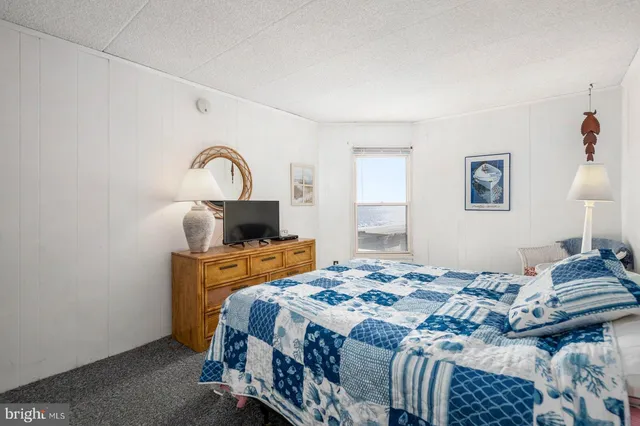 a bedroom with a bed and a lamp on dresser