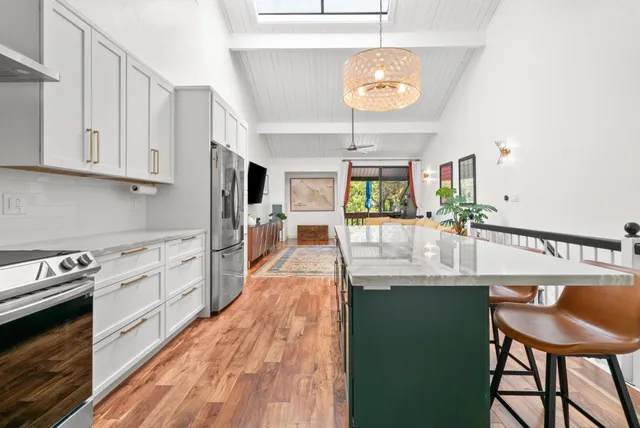 a kitchen with kitchen island granite countertop a stove a sink a dining table and chairs with wooden floor