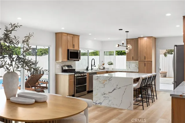 a kitchen with stainless steel appliances granite countertop a stove refrigerator a dining table and chairs with wooden floor