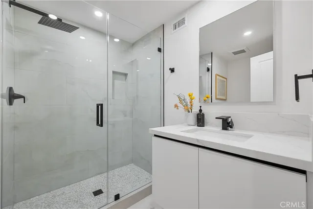 a bathroom with a shower sink vanity and mirror
