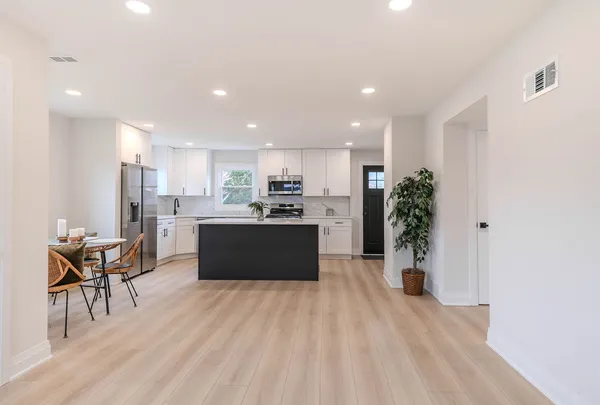 a room with stainless steel appliances kitchen island granite countertop a refrigerator and a sink