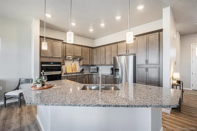 a kitchen with stainless steel appliances granite countertop a sink refrigerator and cabinets