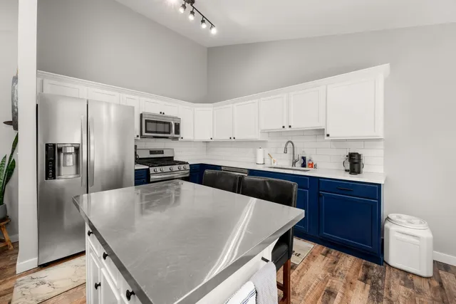 a kitchen with granite countertop a sink a counter space stainless steel appliances and cabinets