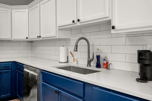 a kitchen with white cabinets and sink