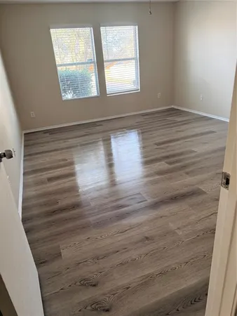 a view of empty room with window and wooden floor
