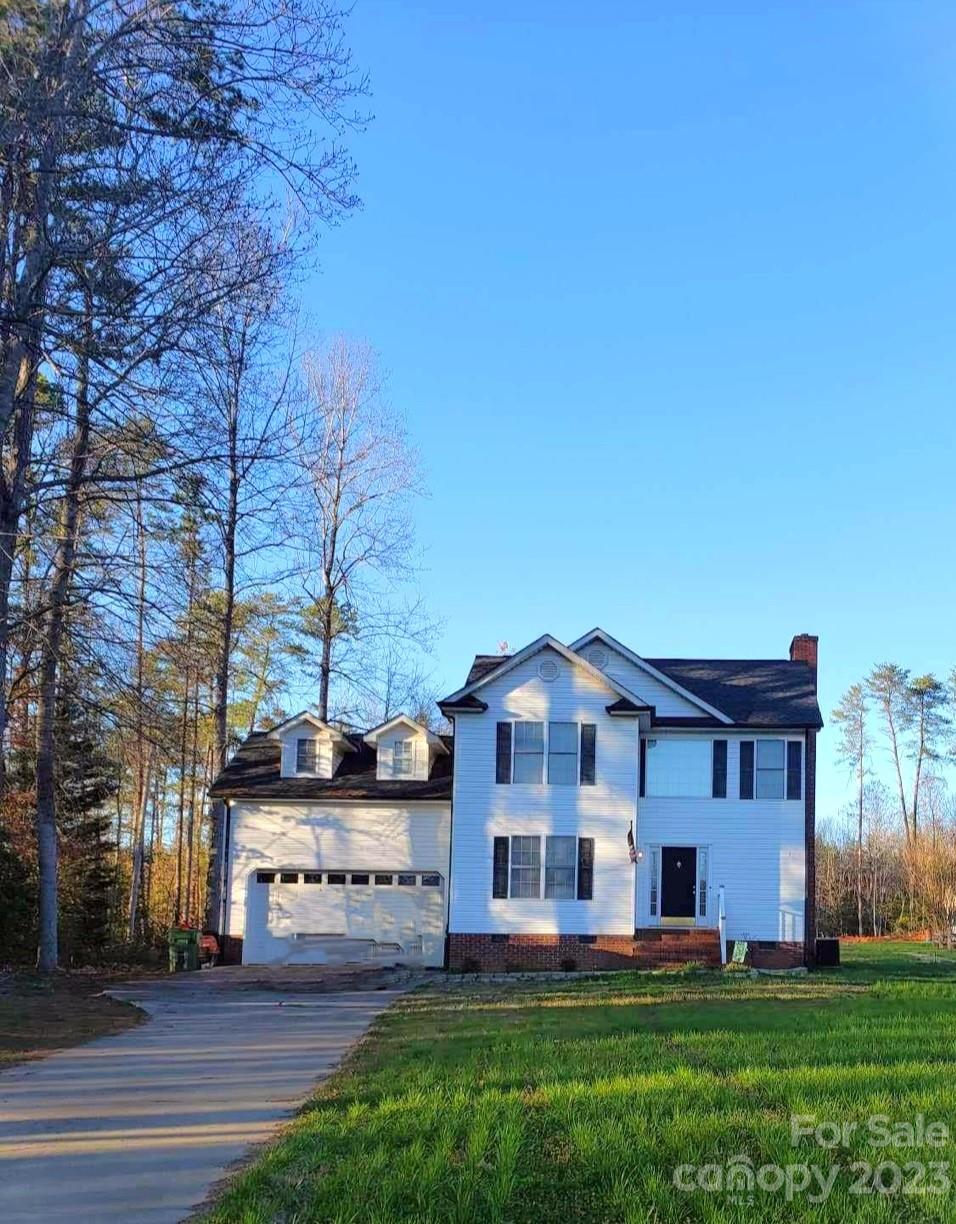a view of a big house with a big yard and large trees