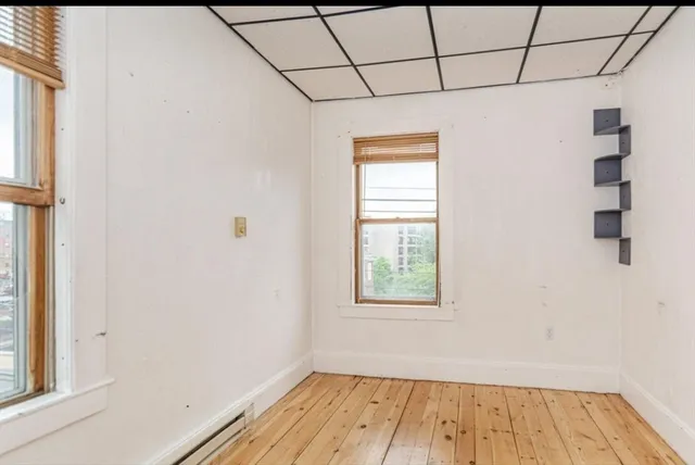 a view of a room with wooden floor and small window