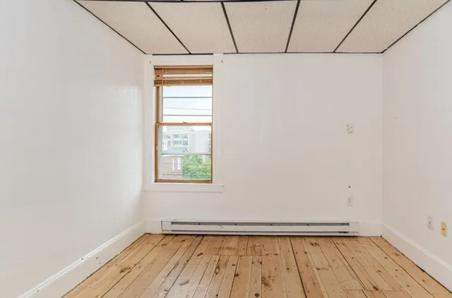 a view of an empty room with a window and wooden floor