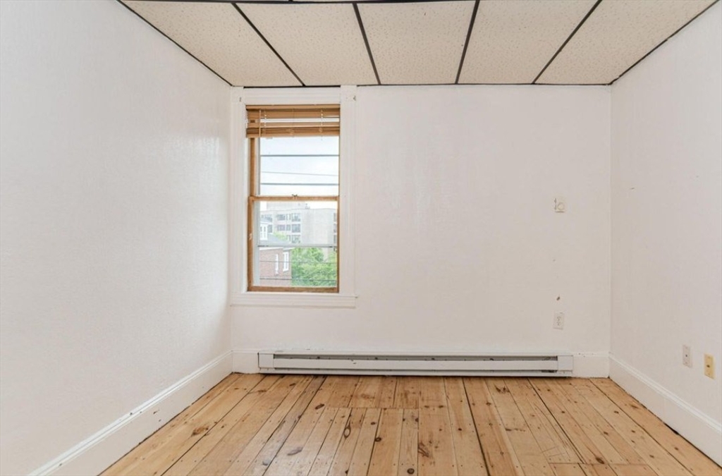 304 Pawtucket Street, Unit 2 Lowell, MA 01854 - Photo 10 of 16 a view of an empty room with a window and wooden floor