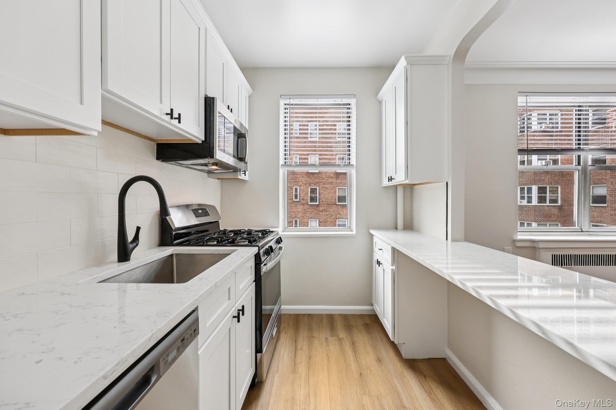 a kitchen with granite countertop a sink a counter space and stainless steel appliances