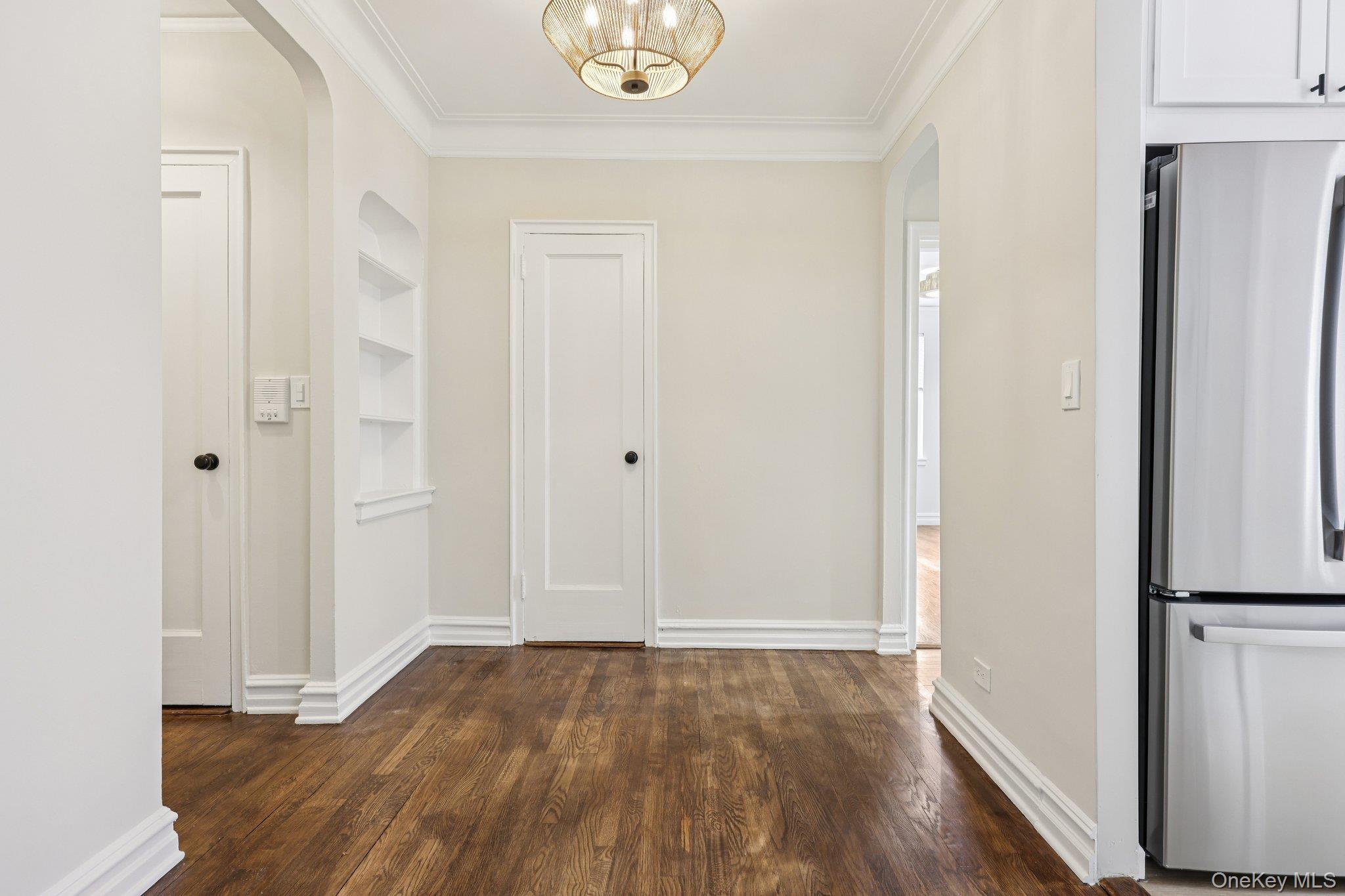 1 Bronxville Road, Unit 3S Bronxville, NY 10708 - Photo 7 of 27 Corridor with arched walkways, ornamental molding, dark wood-style floors, and built in shelves