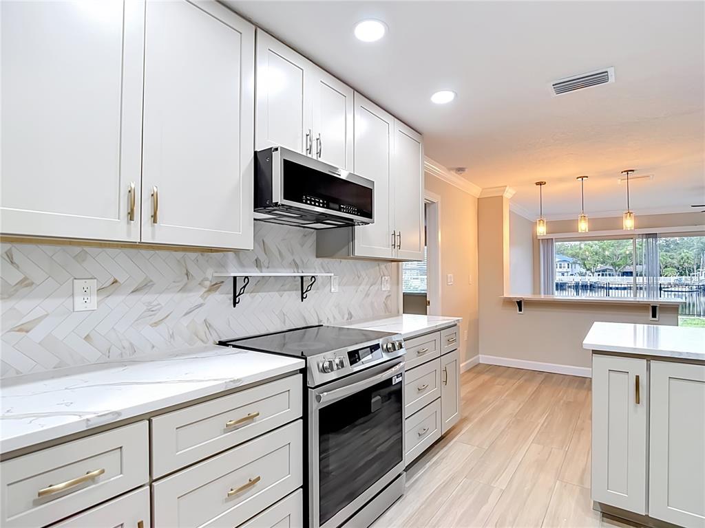 4536 Mitcher Road New Port Richey, FL 34652 - Photo 39 of 46 a kitchen with stainless steel appliances white cabinets and a stove top oven