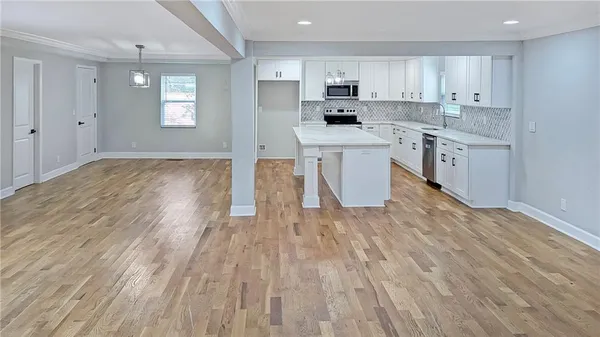 a kitchen with kitchen island wooden floors appliances and cabinets