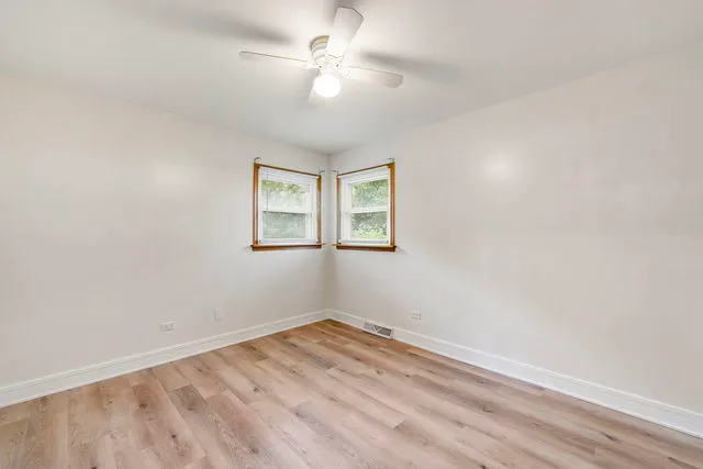 an empty room with a window and ceiling fan