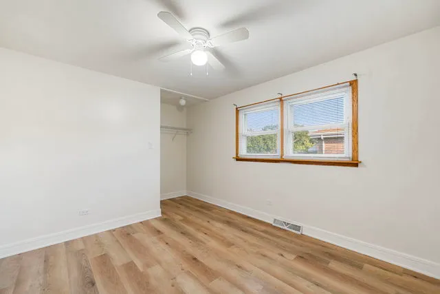 a view of empty room with wooden floor and fan