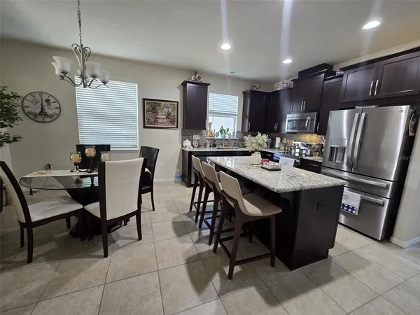 a kitchen with a dining table chairs and refrigerator