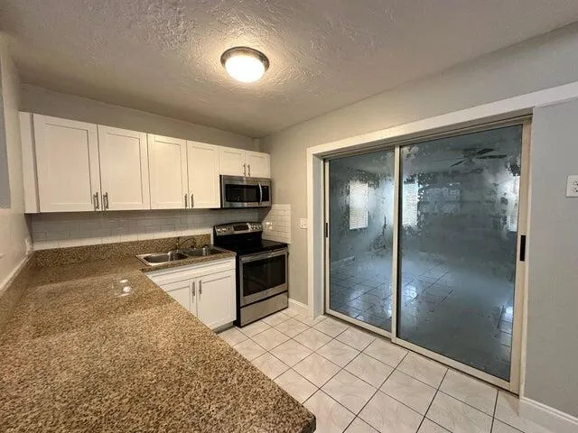 a kitchen with granite countertop a refrigerator and a stove top oven